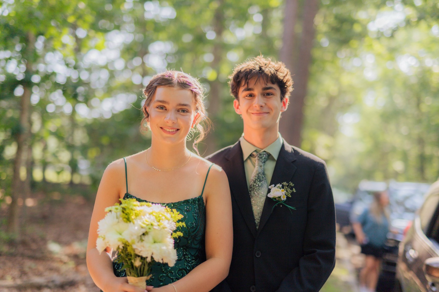 A couple in formalwear on a wooded path